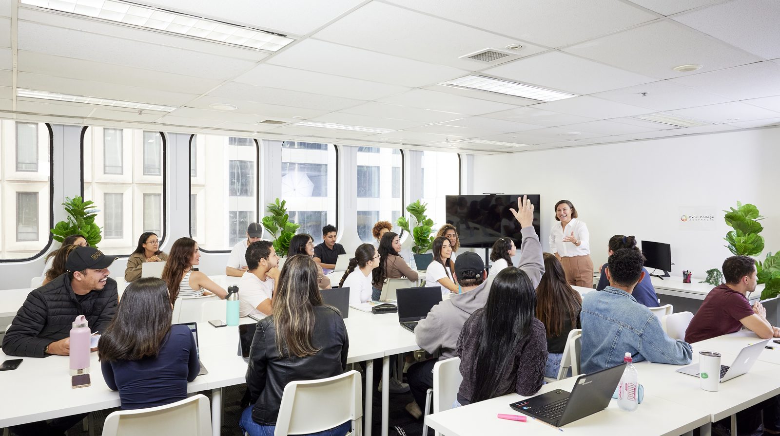 A bright Sydney classroom full of students during a face-to-face training session, with a trainer presenting at the front